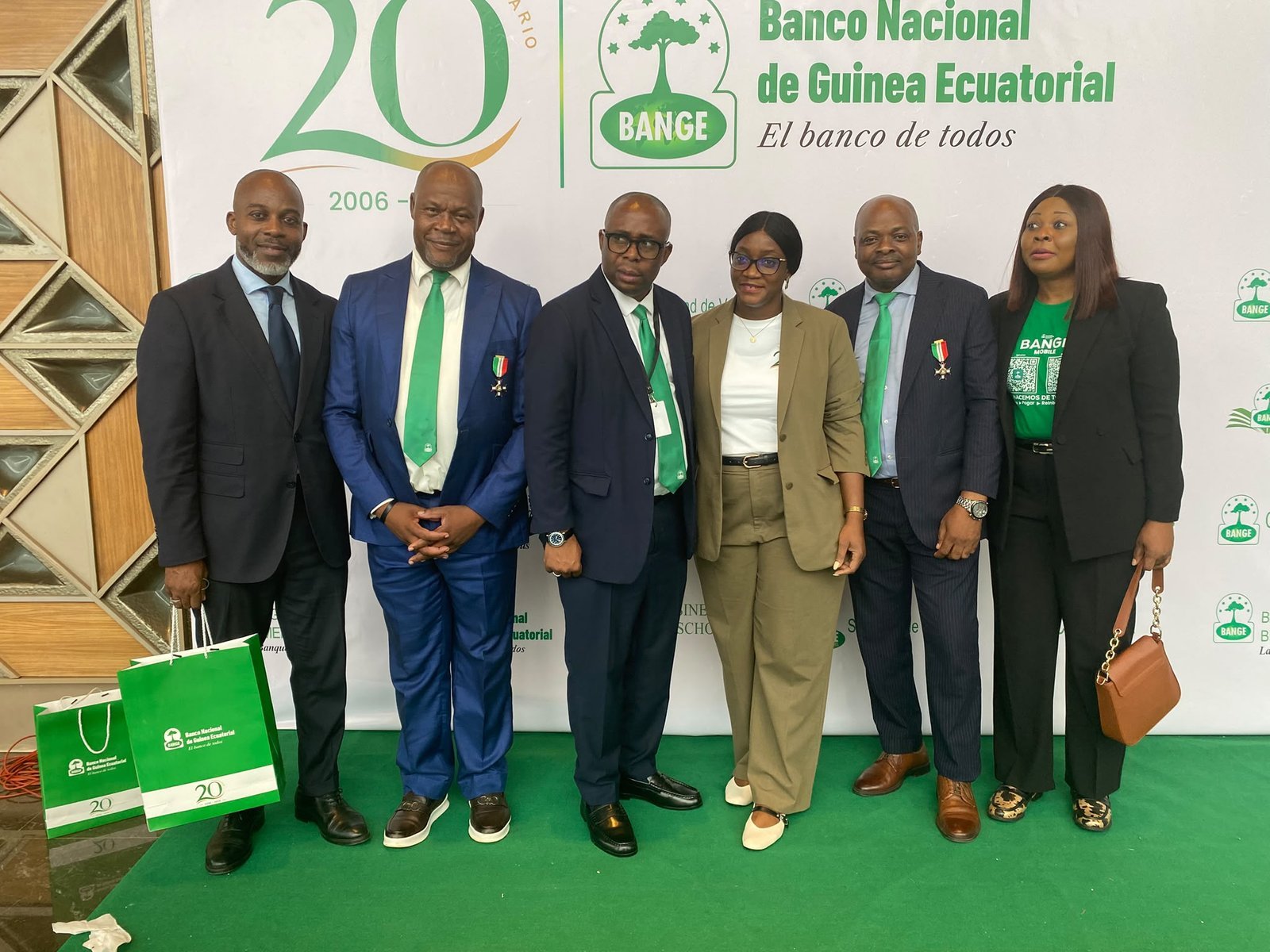 Six participants posent devant la toile de fond du 20e anniversaire de la Banco Nacional de Guinea Ecuatorial.